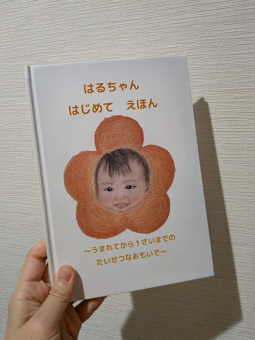 オーダーメイド絵本「はるちゃん はじめて えほん ~うまれてから1さいまでのたいせつなおもいで~」を手に持っている